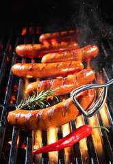 Delicious sausages sizzling over the coals on barbecue grill
