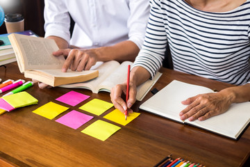 Young students classmates help friend catching up workbook and learning tutoring in a library, education and school concept