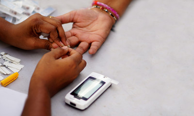 closeup of Doctor piercing the finger of patient with lancet to check blood sugar level