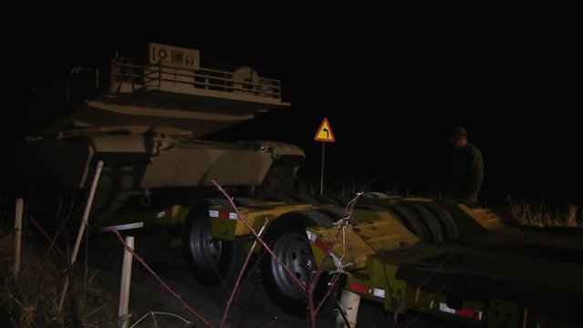 M1 Abrams tank driving onto lowbed trailer at night