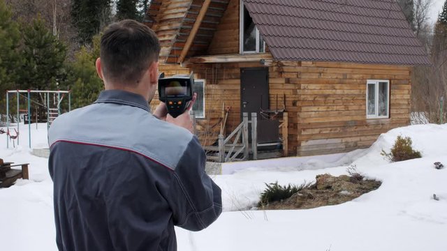 The worker carries out an inspection of the house the thermal imager. To look for losses of heat. Fight against heatlosses. Energy saving.