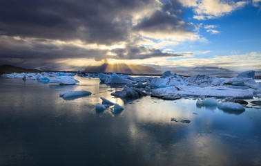 Fototapeta na wymiar Dramatic a sunset with mirror water with blue iceberg pieces in Jokulsarlon lagoon, Iceland.
