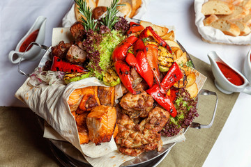 Mixed grill meat, fried vegetables and grilled salmon fish fillets decoration in warm dish. Assorted delicious grilled kebab served with herbs on platter. Restaurant menu plate