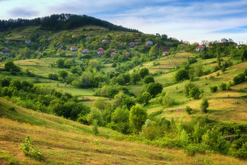 Fototapeta na wymiar Spring is coming... Amazing spring view with a little village in Rhodopi Mountains, Bulgaria. Magnificent landscape, green fields, small houses.