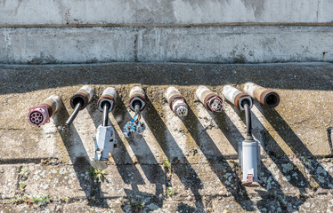 Old damaged electric plug power line installations on the river shore or ocean marine for yachts ...