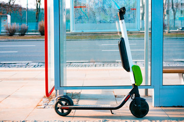 Electric scooter stands near public bus stop. Electric scooters stand along the streets of...