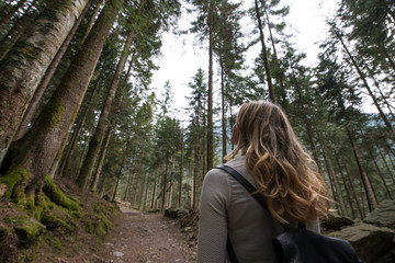 Young beautiful woman looking the trees of the forest while hiking