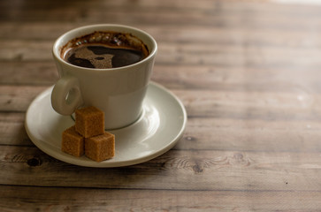 White Cup of coffee on wood natural background cane sugar pieces on plat