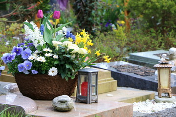 Am Friedhof, Grabpflege, ein frühlingshaft bepflanzter Blumentopf und zwei Grablaternen