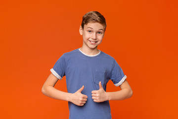 Cool boy doing thumbs up gesture on orange