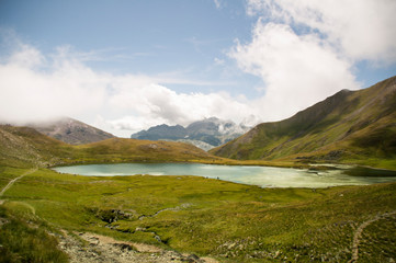 Fototapeta na wymiar Panorama de montaña con lago y nubes al fondo