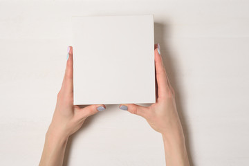 Small white cardboard box in female hands. Top view. White background