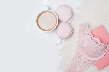 Cup of coffee with marshmallows. Pink lace bodice and notepad on white background. Fashionable concept.