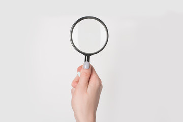Female hand holding magnifier isolate on light background.