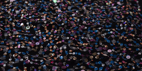 Texture of black cloth with colorful sequins. Close-up.
