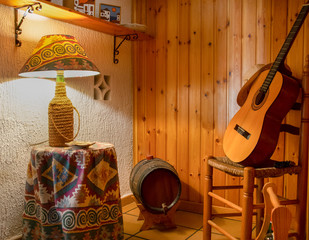 Espacio del hogar destinado a guardar vino en una tinaja junto a una guitarra clásica.