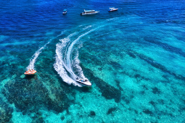 Yachts at the sea in Bali, Indonesia. Aerial view of luxury floating boat on transparent turquoise...