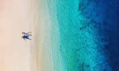 Aerial view of a people couple on the beach on Bali, Indonesia. Vacation and adventure. Beach and turquoise water. Top view from drone at beach, azure sea and relax couple. Travel and relax - image - Powered by Adobe