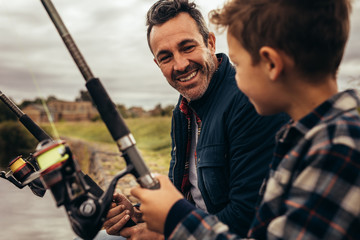 Father and son sitting near a lake fishing