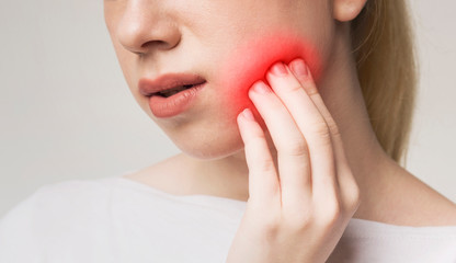 Woman suffering from toothache, touching inflamed cheek