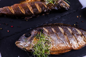 Grilled fish with lemon and spices. Healthy food or diet nutrition concept. Fish Meat on a Black Tray