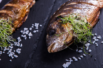 Grilled fish with lemon and spices. Healthy food or diet nutrition concept. Fish Meat on a Black Tray