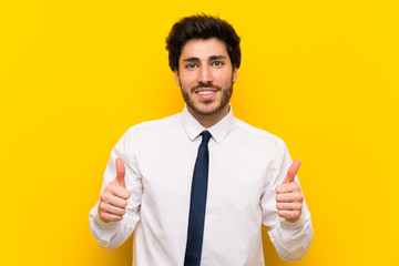 Businessman on isolated yellow background giving a thumbs up gesture