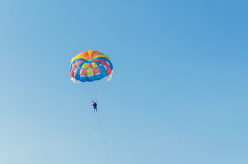 Fototapeta na wymiar Parasailing is an extreme sport, people fly by parachute against the blue sky