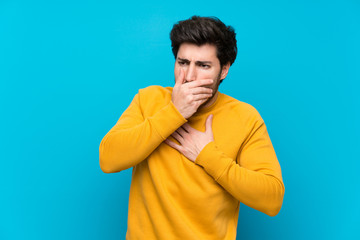 Handsome over isolated blue wall is suffering with cough and feeling bad