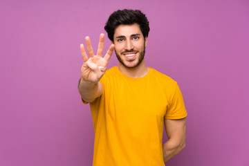 Fototapeta premium Handsome over isolated purple wall happy and counting four with fingers