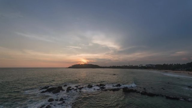 Sunset at Sri Lanka beach Mirissa in the south coast. Clouds rush by and turn orange during golden hour in this 4K time-lapse