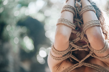 Woman bound with a rope in Japanese technique shibari outdoors