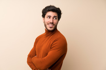 Handsome over isolated wall with arms crossed and happy