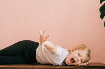 Lifestyle portrait of clowning little girl make faces and shouting on pink wall background. Funny...