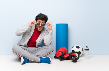 Sport man sitting on the floor with glasses and surprised