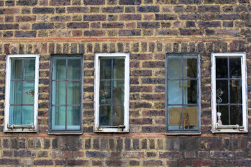 Several small vintage windows in a brick antique wall. Street photo.