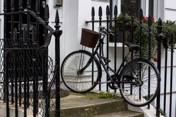 Vintage bicycle with basket on the porch. Entrance Door to residential building in London. Typical door in the English style