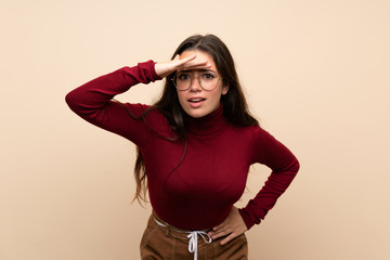 Teenager girl with glasses looking far away with hand to look something