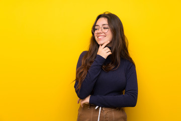Teenager girl over isolated yellow wall looking to the side