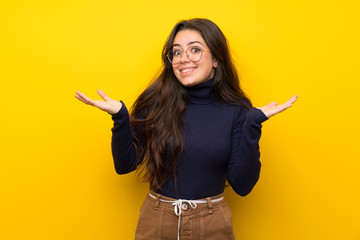 Teenager girl over isolated yellow wall making doubts gesture