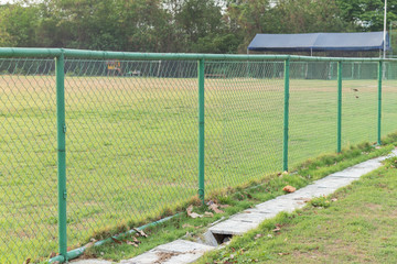 green metal fence at grass football field