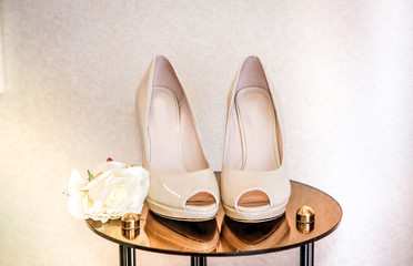 Fototapeta na wymiar Wedding shoes with high heels are on the mirror table