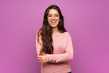 Teenager girl over purple wall keeping the arms crossed in frontal position