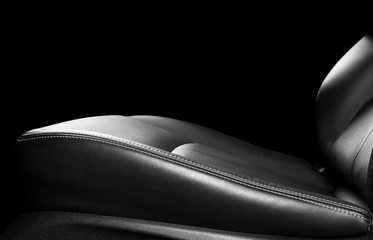 Car black leather seat isolated on black background. Part of leather car seat details with...