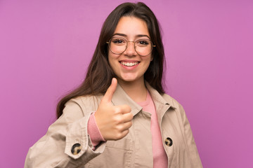 Teenager girl over purple wall giving a thumbs up gesture