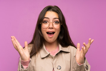 Teenager girl over purple wall with surprise facial expression