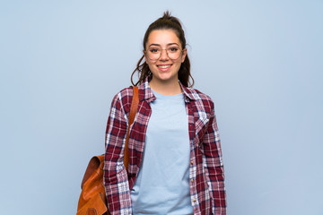 Teenager student girl over isolated blue wall with glasses and happy