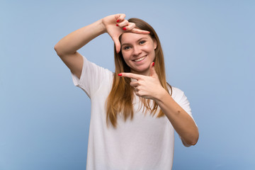 Young woman over blue wall focusing face. Framing symbol
