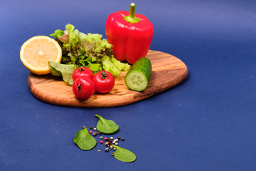 fresh vegetables and a bowl of salad with mozzarella on a blue background.  Caprese salad . Lettuce, cherry tomatoes, mozzarella, 