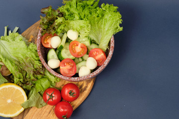 fresh vegetables and a bowl of salad with mozzarella on a blue background.  Caprese salad . Lettuce, cherry tomatoes, mozzarella, 